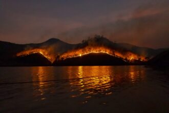 Imagen de una montaña ardiendo al pie de un lago