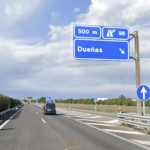 Carretera con dos carriles de circulación, con cartel azul que indica que la salida 96 en dirección a Dueñas está a 500 metros y con una furgoneta circulando por el carril derecho.