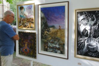 Un hombre contempla varios cuadros en una edición anterior de Expo Aire.
