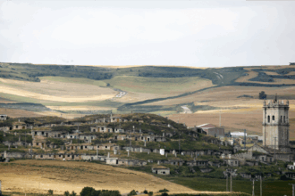 Panorámica del barrio de bodegas de Baltanás, con los campos de cultivo al fondo y la torre de la iglesia a la derecha.