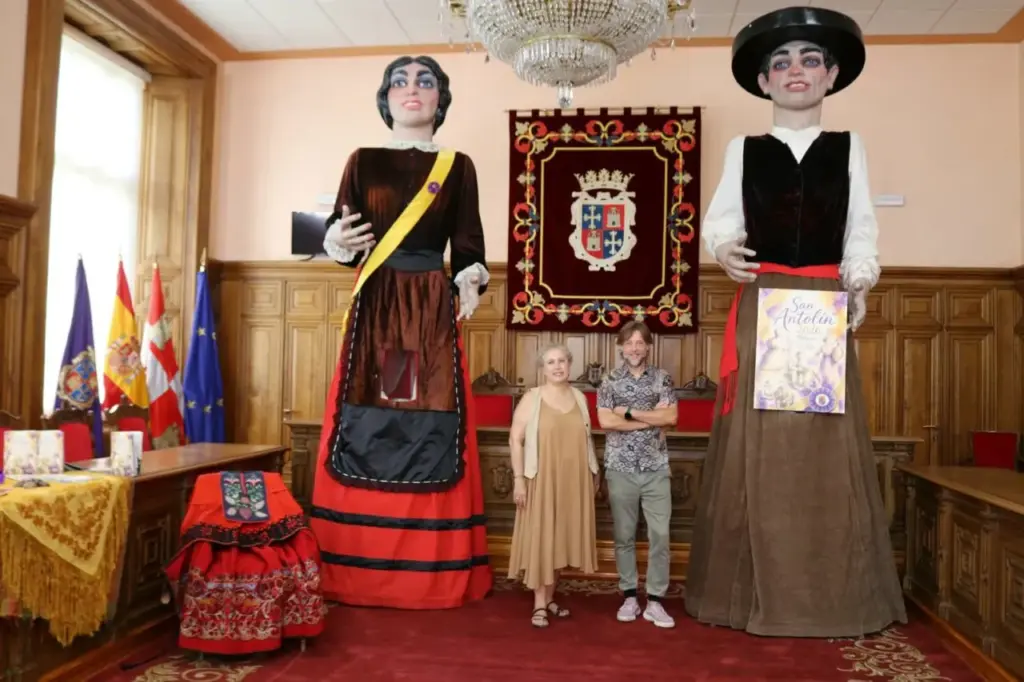 El concejal de fiestas posa delante de dos gigantes y cabezudos.