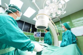 Mesa de operaciones con varios profesionales sanitarios mirando una pantalla con una prueba médica.