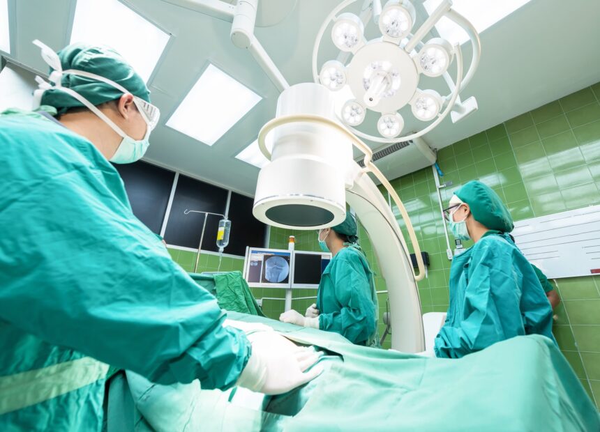 Mesa de operaciones con varios profesionales sanitarios mirando una pantalla con una prueba médica.