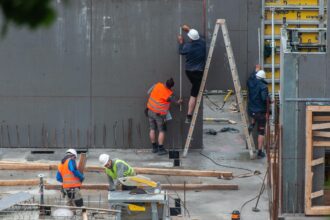 Varios obreros de la construcción trabajan en un edificio realizando diversas tareas.