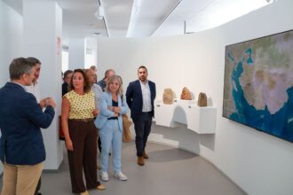 Varias personas charlan ante un mapa geológico en el interior de la casa del Karst.