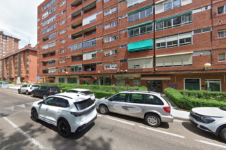 Fachada de edificio en la avenida Reyes Católicos de la capital,con varios vehículos aparcados en línea y otros circulando por la calle.