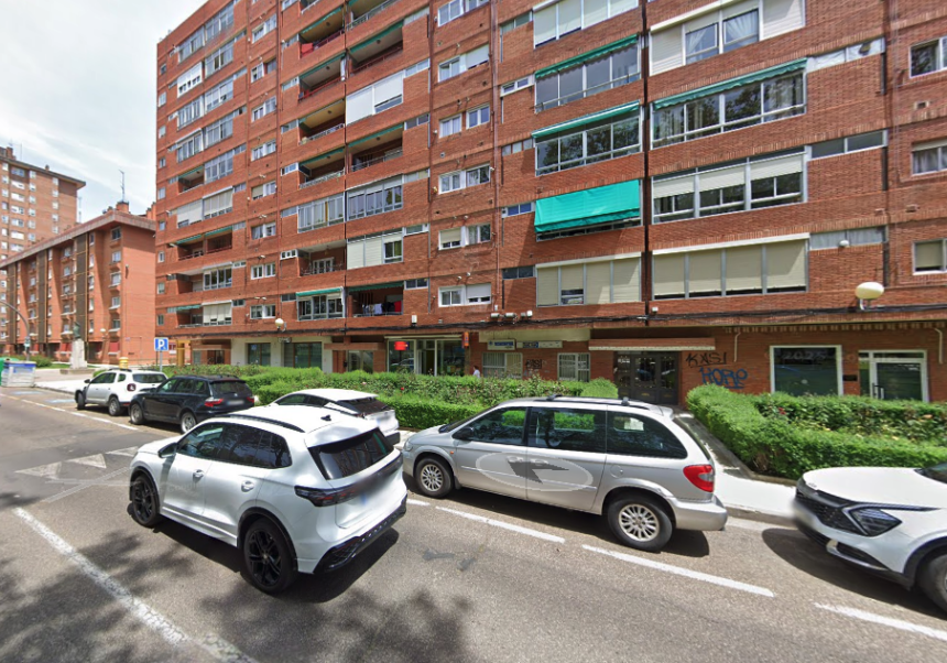 Fachada de edificio en la avenida Reyes Católicos de la capital,con varios vehículos aparcados en línea y otros circulando por la calle.