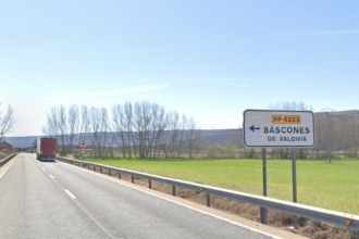 carretera nacional con un camión circulando por ella y el cartel que indica el desvío a Báscones de Valdivia.