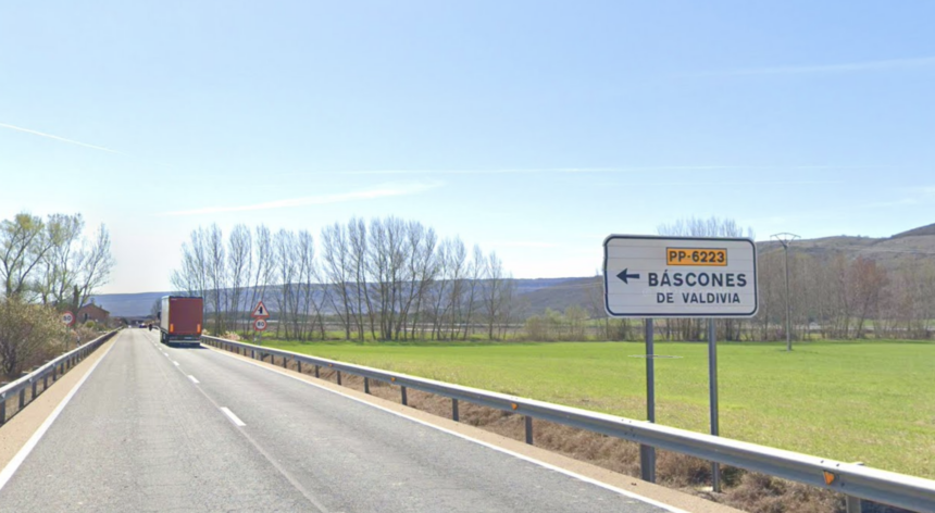 carretera nacional con un camión circulando por ella y el cartel que indica el desvío a Báscones de Valdivia.