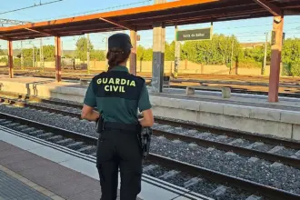 Una mujer Guardia Civil de espaldas observa las vías del tren en la estación de Venta de Baños.