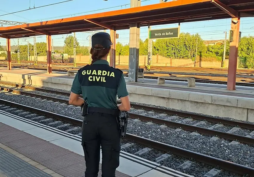 Una mujer Guardia Civil de espaldas observa las vías del tren en la estación de Venta de Baños.