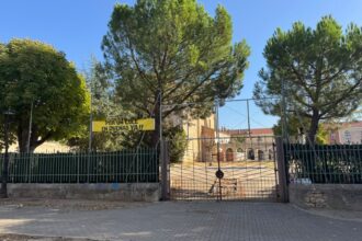 Valla que cierra el solar con la pancarta Por un cole en Dueñas ya, con la valla cerrada.