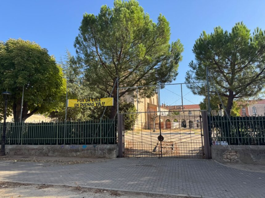 Valla que cierra el solar con la pancarta Por un cole en Dueñas ya, con la valla cerrada.