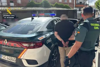 Un himbre esposado es introducido en el interior de un vehículo de la Guardia Civil ante la mirada de dos agentes.