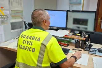 Un guardia civil de tráfico sentado delante de las pantallas del ordenador en una mesa de oficina.