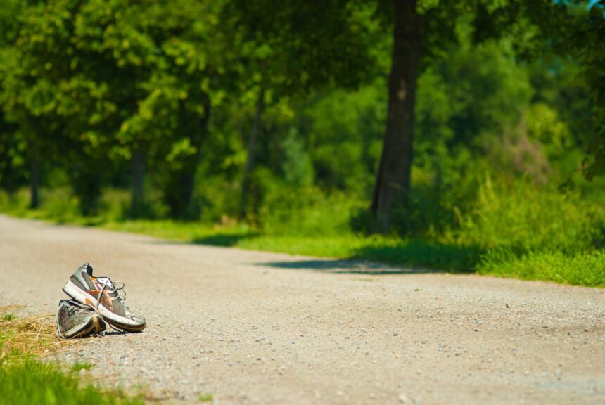 Zapatillas de deporte en mitad de un camino de tierra junto a una zona verde