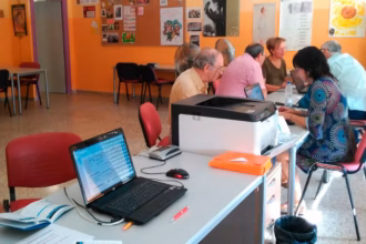 personas sentadas frente por frente a otras con ordenadores portatiles sobre una mesa