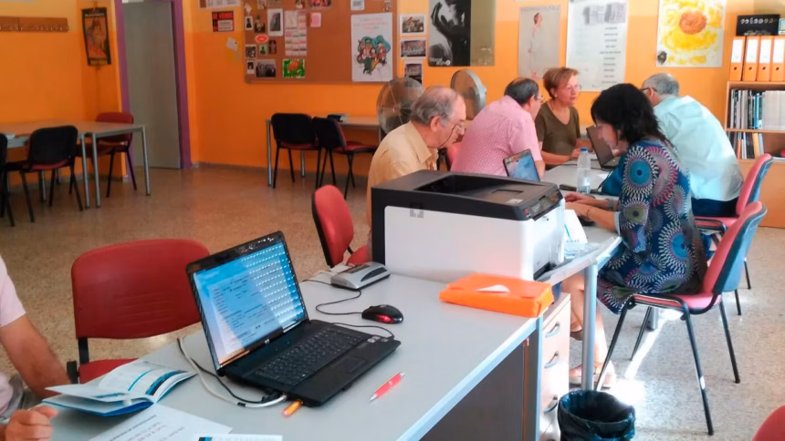 personas sentadas frente por frente a otras con ordenadores portatiles sobre una mesa