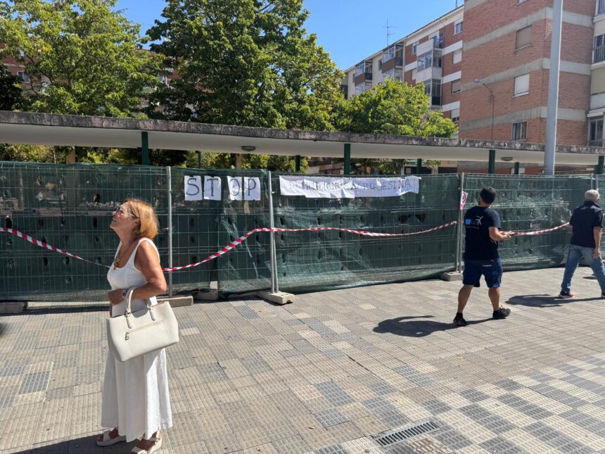 Ciudadanos caminan delante de las vallas de obra que delimitan los trabajos de reforma integral de la plaza Rabí Sem Tob.