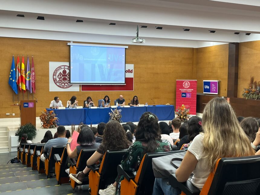 Alumnos sentados en un salón de actos escuchando a los vicerrectores que están ubicados en el escenario.