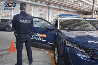 Un Policía Nacional junto a un coche patrulla