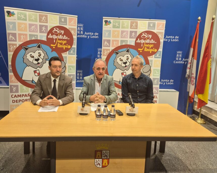 Varias personas sentadas frente a una mesa con varios carteles sobre los Juegos Escolares.