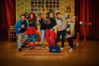 Varios personajes de la obra posan divertidos sobre el escenario