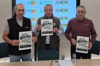 Tres personas sujetan un cartel sobre la próxima movilización de los agricultores.