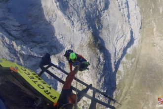 Dos personas son izadas mediante una grúa a un heliocóptero de rescate.