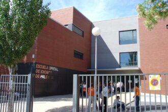 Varias personas tras una verja charlan a la entrada de un edificio