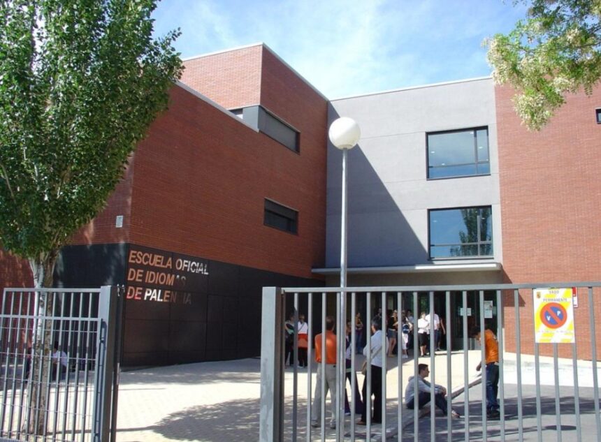 Varias personas tras una verja charlan a la entrada de un edificio