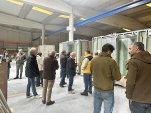 Varias personas charlan en el interior de una fábrica durante una visita.