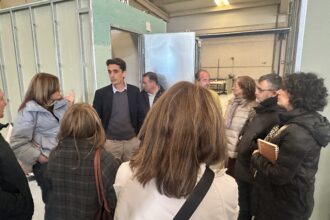 Varias personas escuchan lo que dice otra en la visita a una fábrica