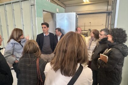 Varias personas escuchan lo que dice otra en la visita a una fábrica