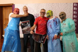 Tres personajes de terror vestidos como enfermos de un hospital bromean junto al concejal de Actividad Física y el presidente del club de atletismo Cuatro Cantones.