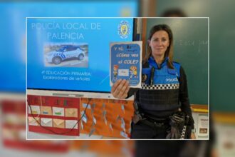 Una mujer policía muestra un tríptico sobre seguridad vial al asistir al cole en un aula escolar