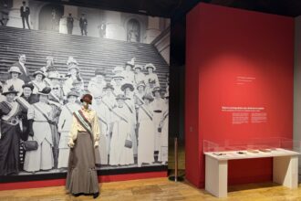 Panel fotográfico de mujeres con una maniquí delante con el atuendo que portaban las sufragistas