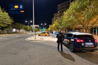 Un Policía Nacional junto a un coche patrulla en una calle de la ciudad