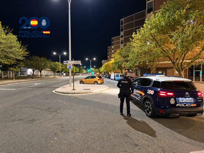 Un Policía Nacional junto a un coche patrulla en una calle de la ciudad