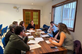 Varias personas dialogan alrededor de una mesa.